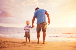 30599267 - father and son standing on the sea shore holding hands at sunset